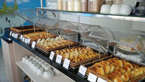 Una vitrina de panadería con diversos productos horneados como rosquillas, croissants y panecillos.