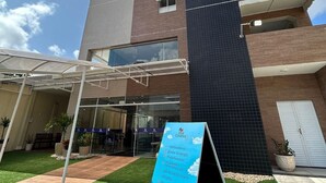Un edificio moderno con entrada de vidrio, un cartel anunciando los servicios y un césped bien cuidado.