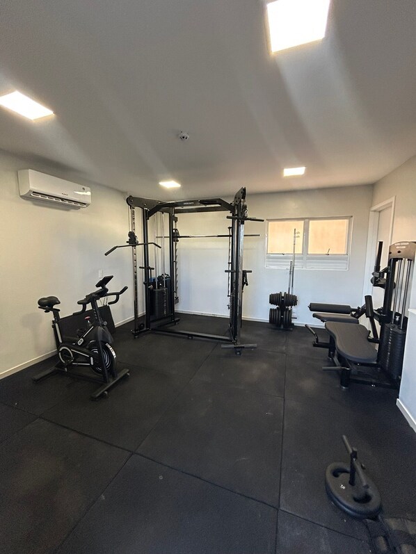 Un gimnasio con una jaula para sentadillas, banca de pesas y una bicicleta estática.