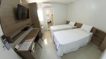 A hotel room with a TV, two beds, a desk, and a bathroom visible through an open door.