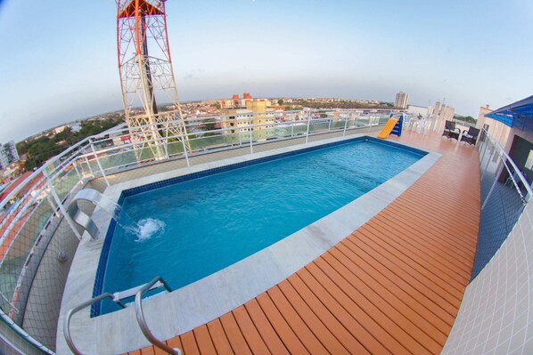 Une piscine sur le pont d’un navire de croisière, avec la ville en arrière-plan.