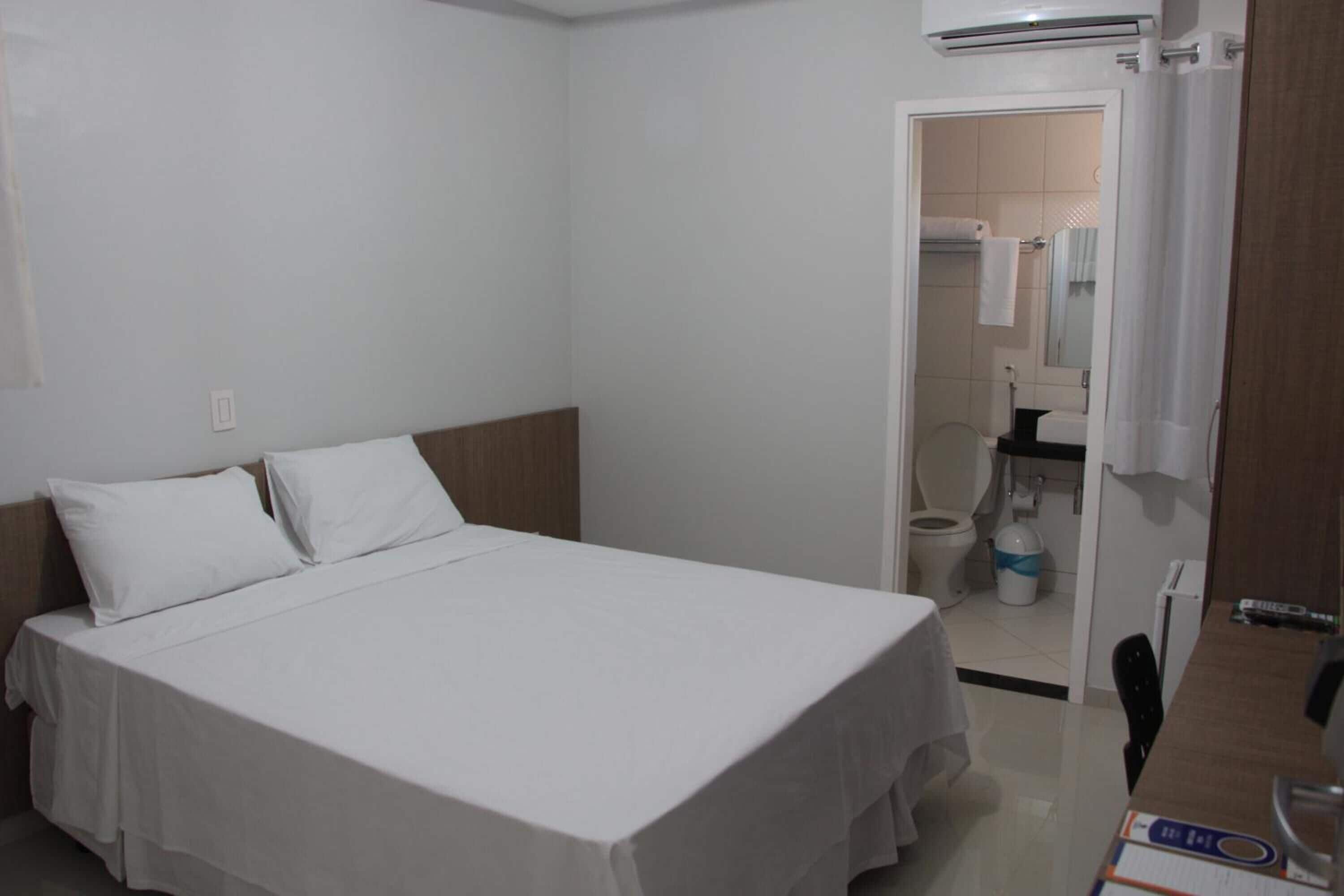 Een hotelkamer met een bed, een bureau en een badkamer, zichtbaar door een geopende deur.