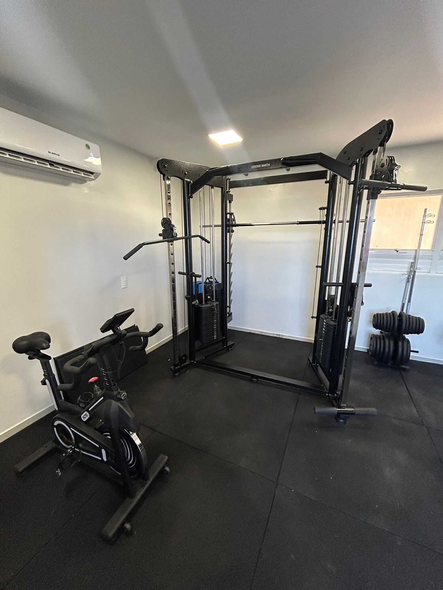 Ein Heimfitnessraum mit Ergometer, Gewichtbank und Squat-Rack.