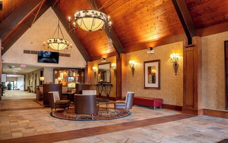 A lobby with wooden beams, a chandelier, a TV, and seating areas.