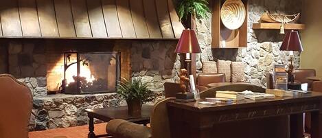 A cozy living room with a stone fireplace, leather furniture, and recessed lighting.