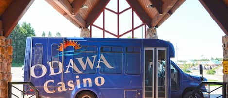 Un fourgon du casino ODAWA, de couleur bleue, était garé sous une structure en bois soutenue par des piliers en pierre.