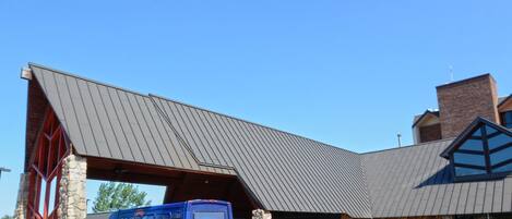 A building with a metal roof and stone pillars, a blue van with "Odawa Casino" text, and a clear blue sky.