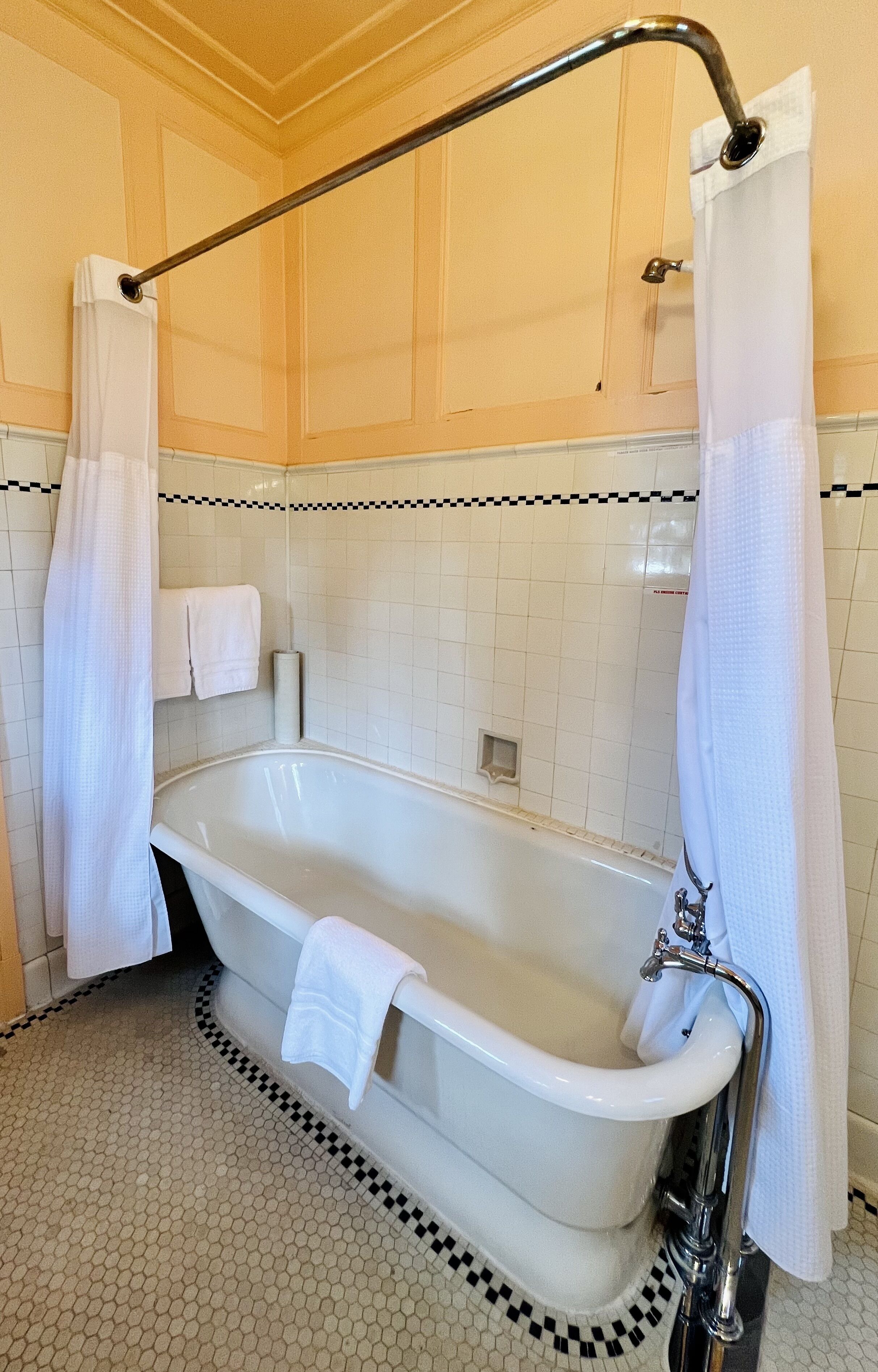 A bathroom with a white bathtub, a shower curtain, and a towel rack.
