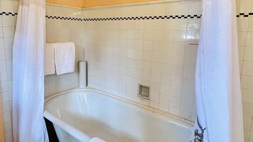 Een badkamer met een witte badkuip, douchegordijn en handdoekhouder.
