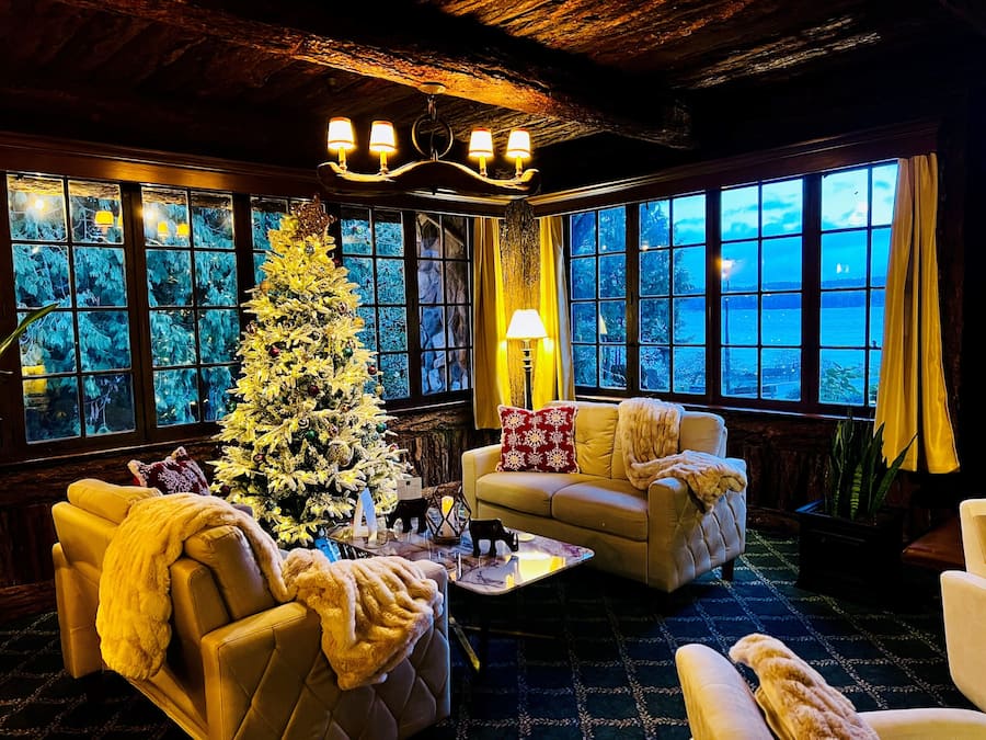 Una habitación acogedora con un gran árbol de Navidad, sofás de cuero, una chimenea y vistas al mar a través de amplios ventanales.
