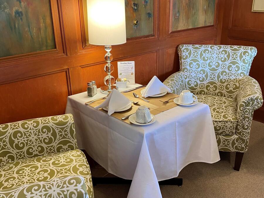 A dining area with a table set for two, a lamp, and a breakfast menu.