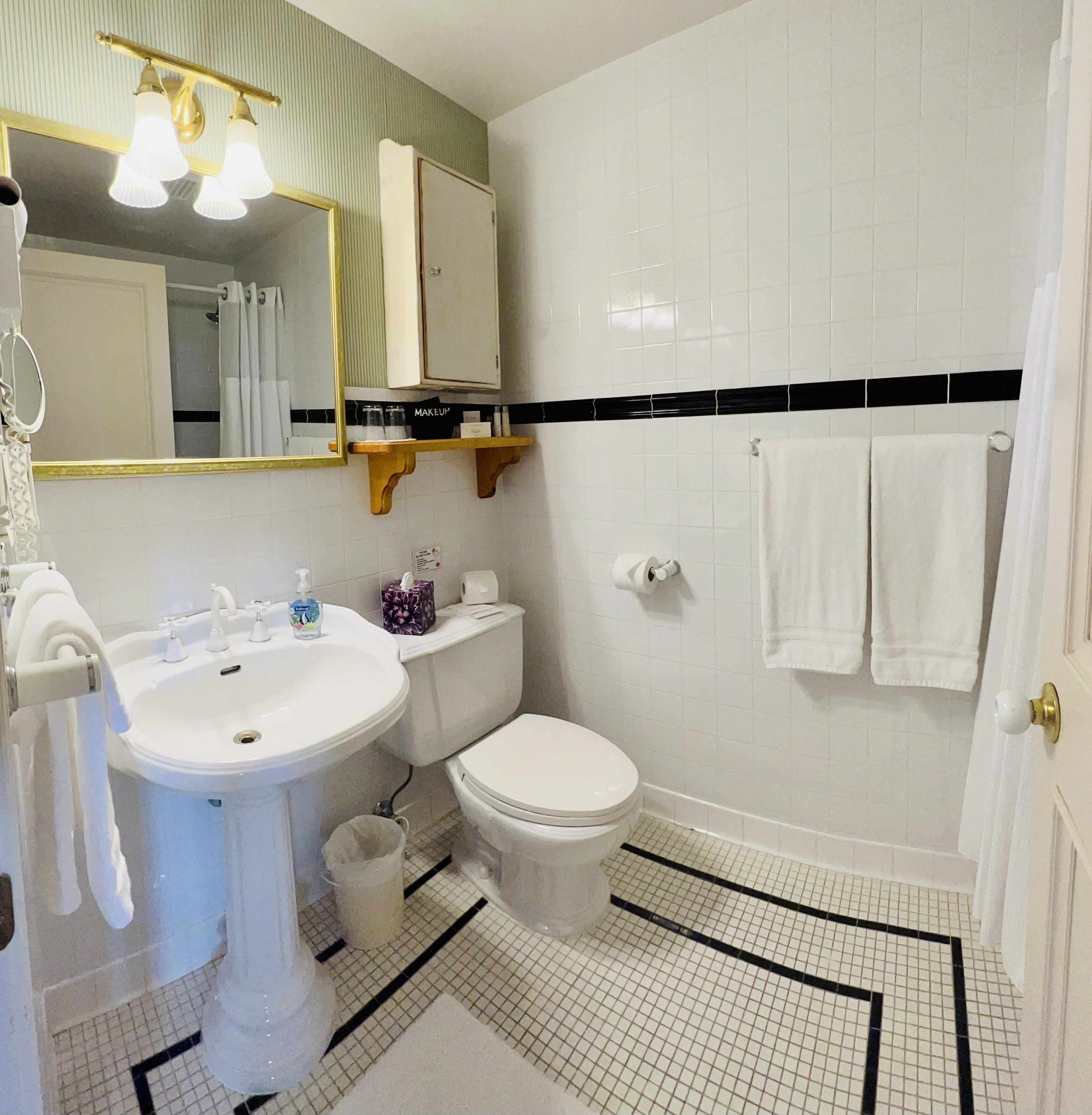 A bathroom with a white sink, a toilet, a mirror, and a shower curtain.