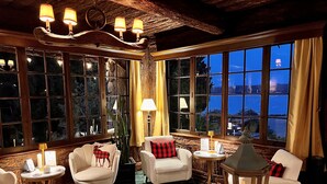 A cozy room with a fireplace, large windows, and comfortable seating. - The Latch Inn (Sidney)
