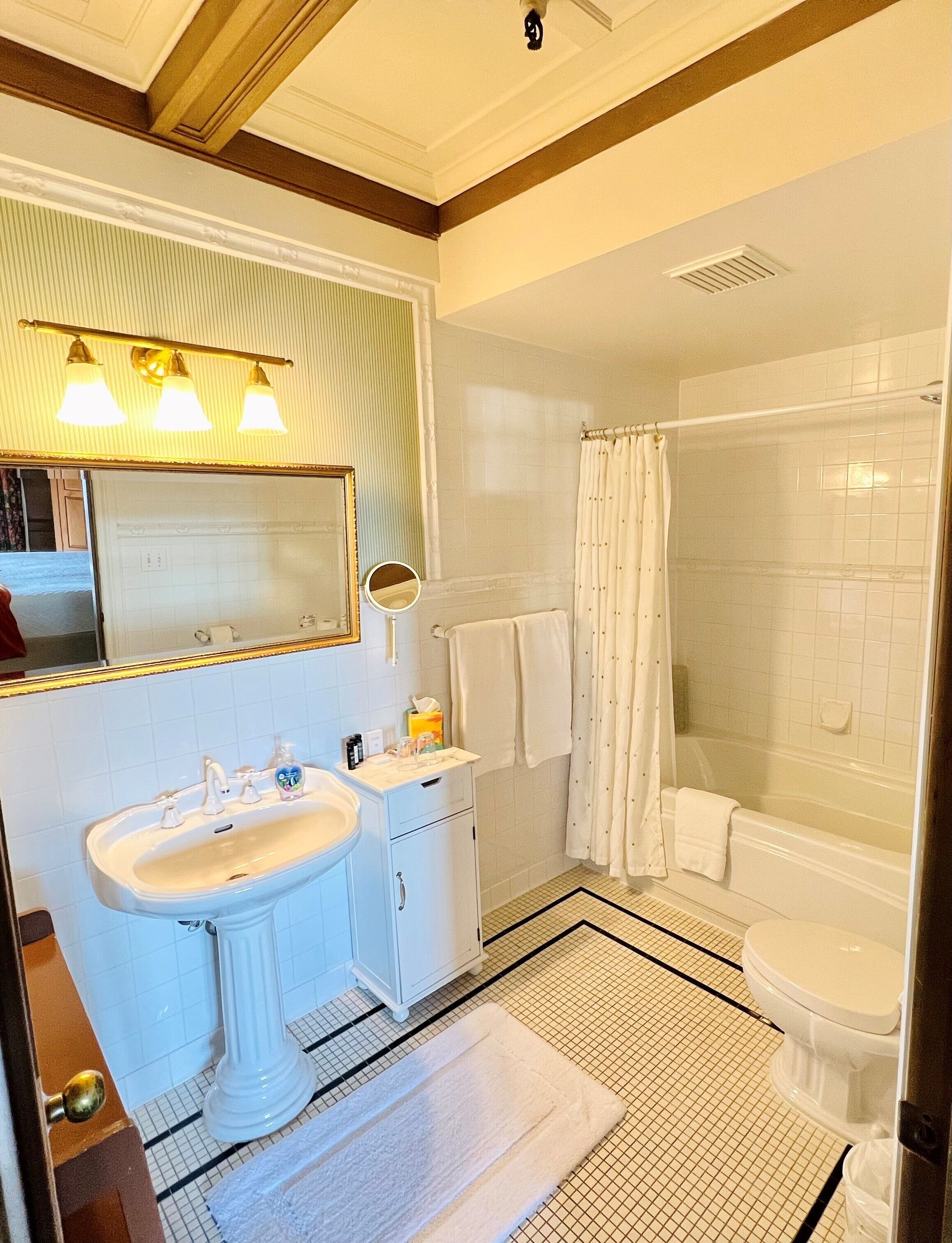 A bathroom with a sink, mirror, and shower.