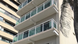Een hotel met meerdere verdiepingen, balkons, een zwembad en potplanten.