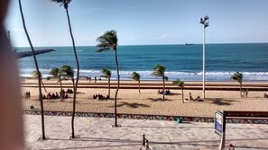 A beach with palm trees, a volleyball net, and a ship in the distance. - Brisa da Praia Hotel (Fortaleza)