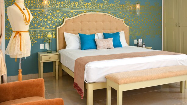 A bedroom with a bed, a nightstand, a dresser, a mannequin, and a chair. - Unic Design Hotel - Near Mamitas Beach Club (Playa del Carmen)
