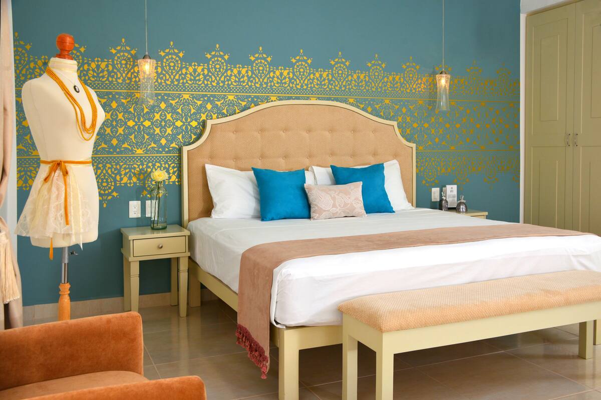 A bedroom with a bed, a nightstand, a dresser, a mannequin, and a chair.