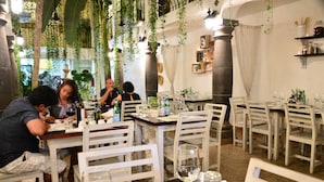 A restaurant with white chairs and tables, hanging plants, and a stone column. - Unic Design Hotel - Near Mamitas Beach Club (Playa del Carmen)