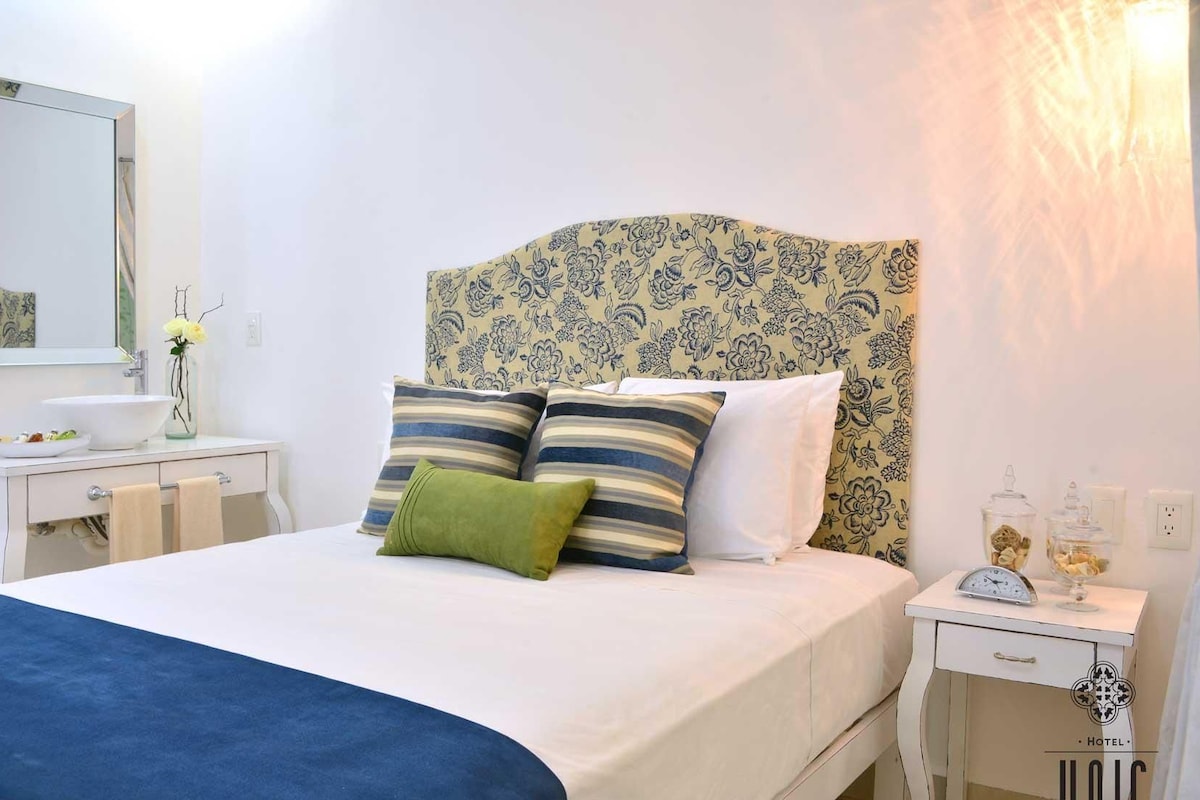Une chambre à coucher avec un lit, des tables de chevet, un miroir et une petite table de nuit.