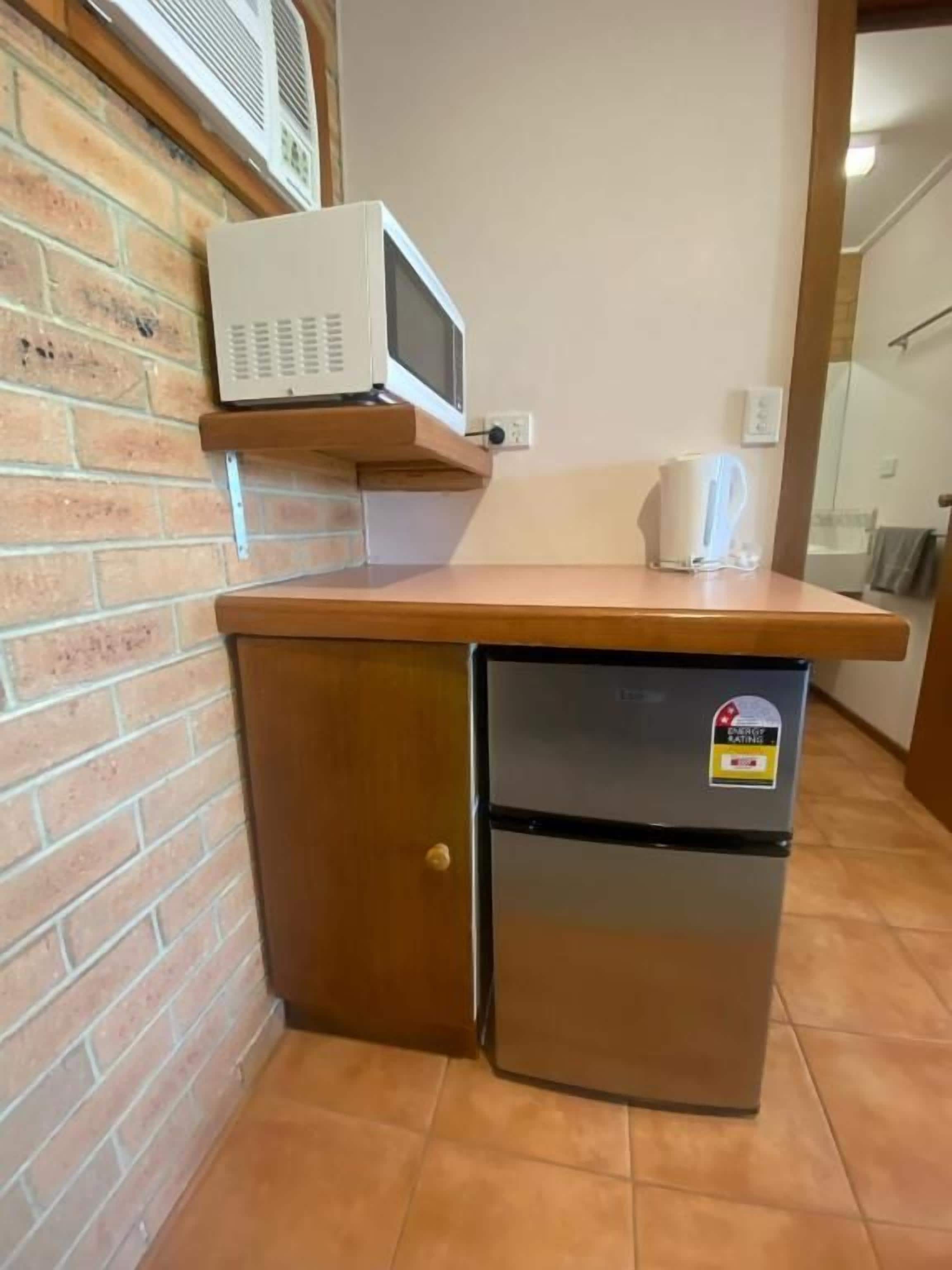 A compact kitchenette with a microwave, a coffee maker, and a refrigerator.