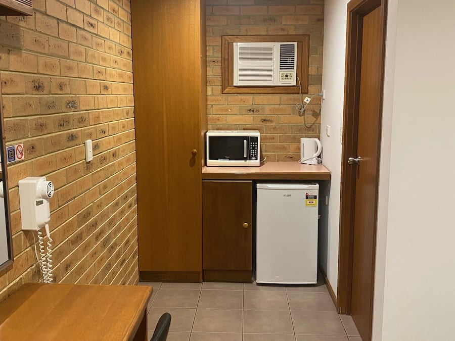 Una cocina compacta con microondas, un refrigerador pequeño y aire acondicionado integrado.