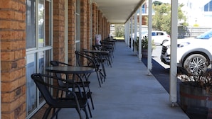 A covered outdoor seating area with brick walls and tables. - Quays Motel San Remo (San Remo)