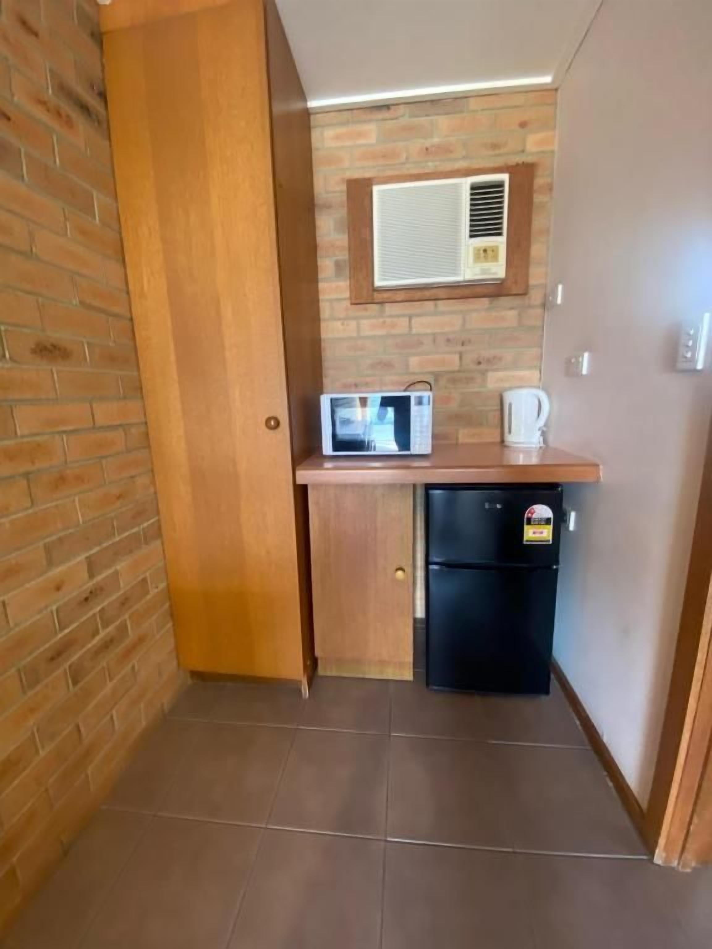 Cocina compacta con refrigerador, microondas y cafetera sobre la encimera.