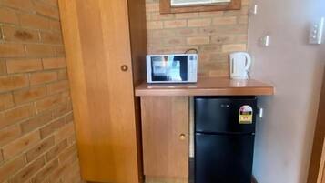 Cocina compacta con refrigerador, microondas y cafetera sobre la encimera.