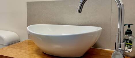 A white ceramic sink with a modern chrome faucet on a wooden countertop.