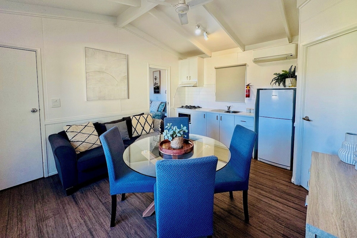 A compact kitchen with white cabinets, a built-in stove, and a refrigerator.