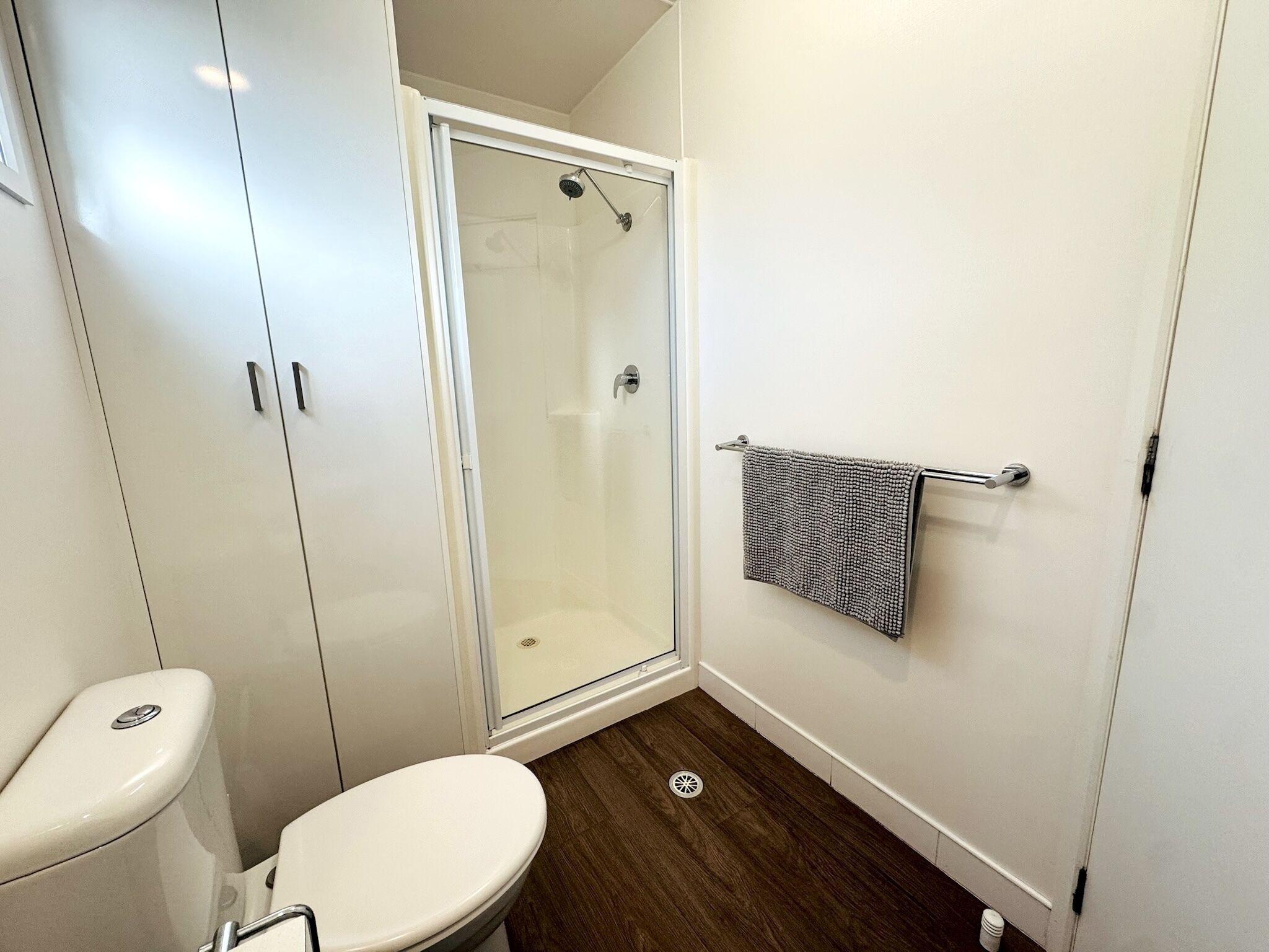 A bathroom with a toilet, a shower enclosure, and a towel rack.