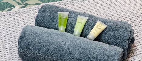 A rolled-up towel with three spa products on a textured surface.