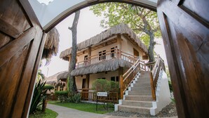 A reception area with a staircase leading to a building with a thatched roof. - Kav's Beach Resort (Zamboanguita)