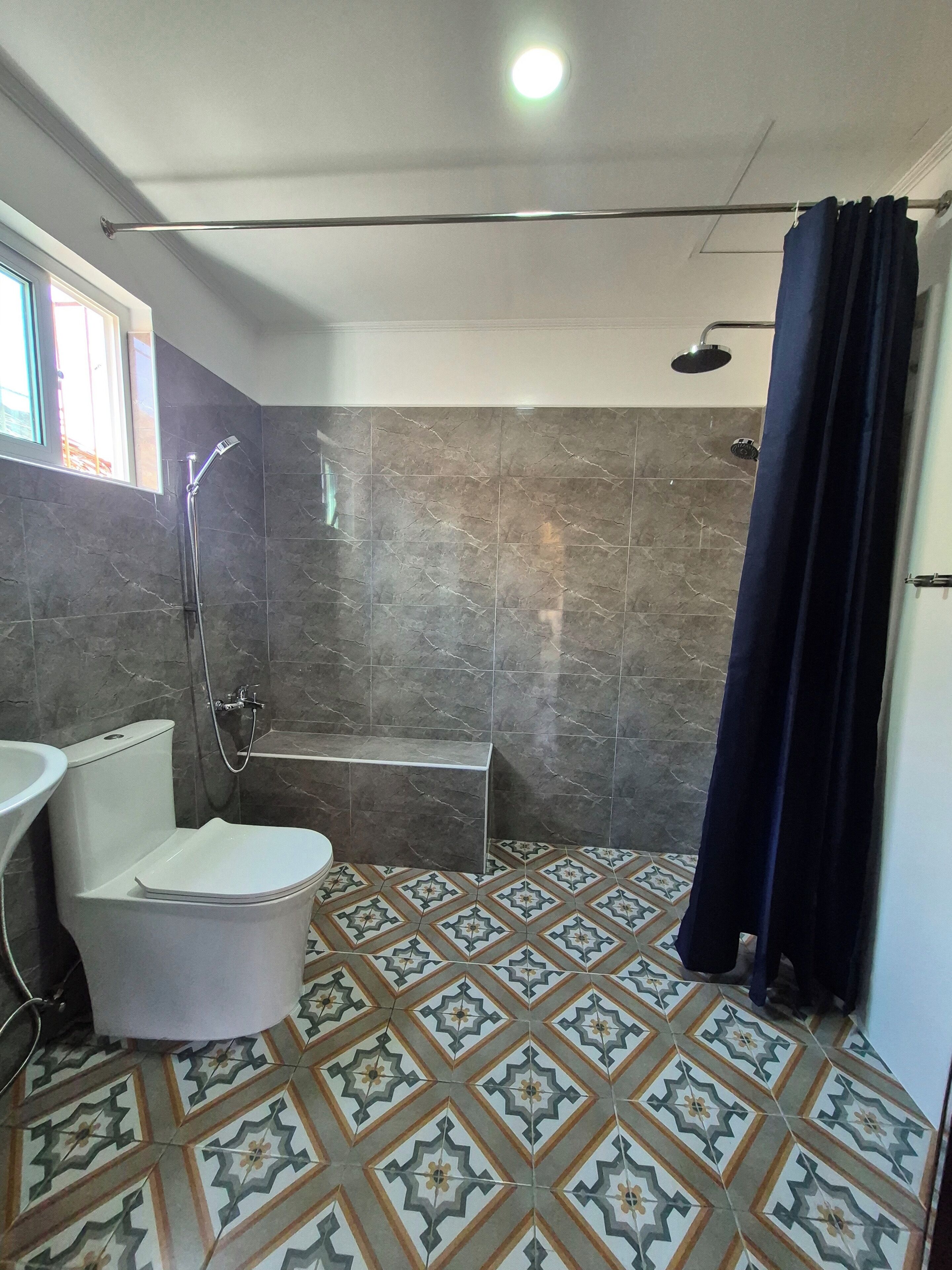 A bathroom with a bathtub, a shower, and a toilet. The floor has a patterned tile design.