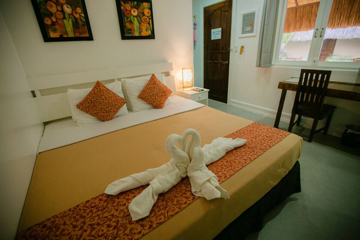 A hotel room with a bed, a desk, and a chair.