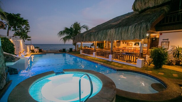 A swimming pool with a hot tub, a bar area, and a thatched-roof structure. - Kav's Beach Resort (Zamboanguita)