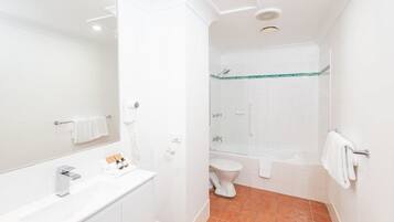 A modern bathroom with a white vanity, a large mirror, a toilet, and a shower area.