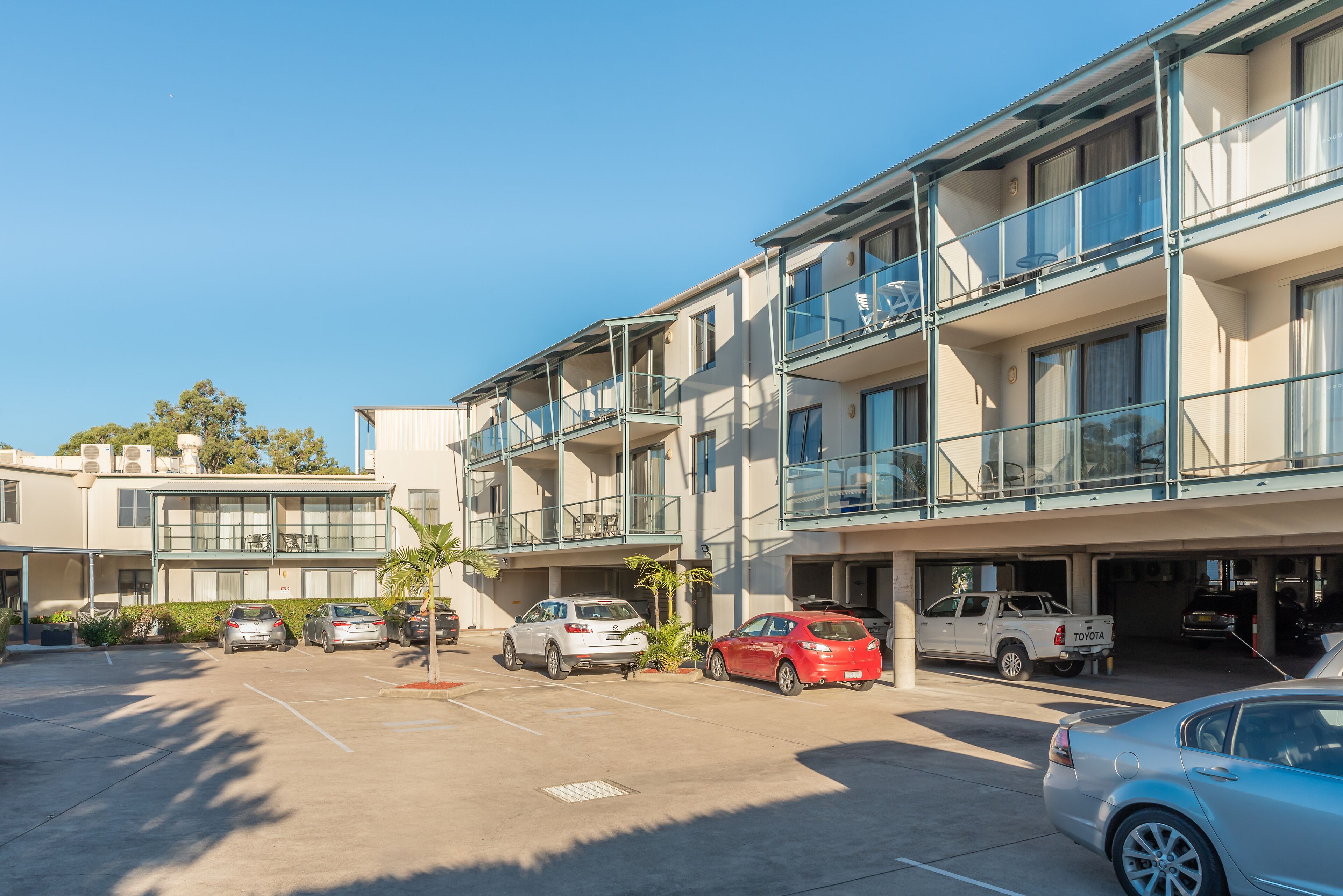 A multi-story parking garage with several cars parked, including a white SUV and a red sedan.