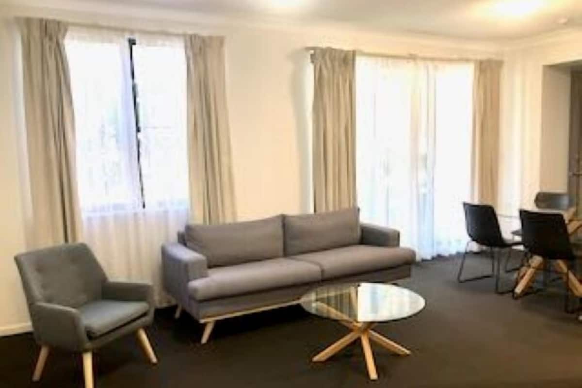 A modern living room with a grey sofa, a round coffee table, and two armchairs.