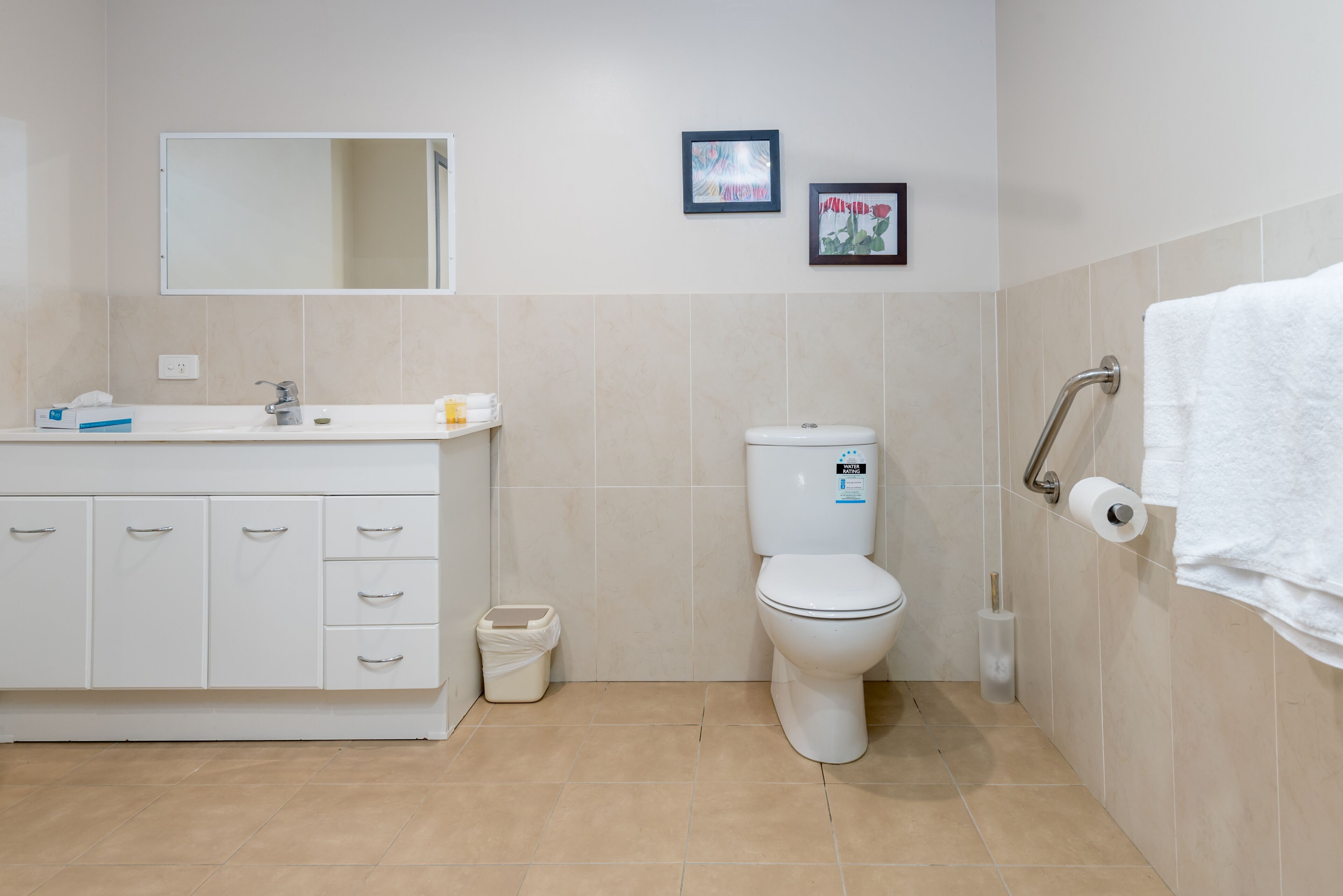 A bathroom with a white sink, mirror, toilet, and a towel rack.