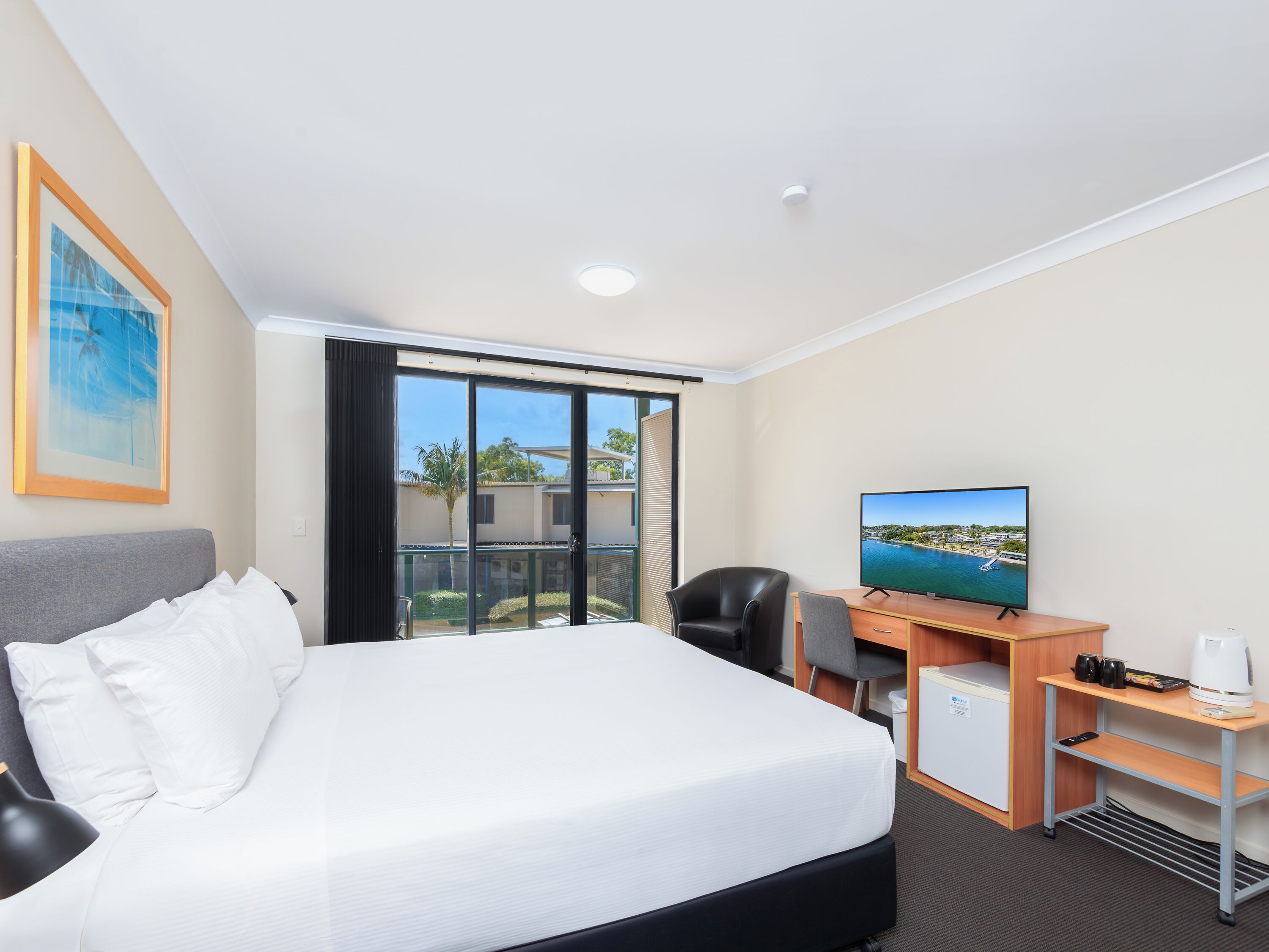 Una habitación de hotel con cama, escritorio, televisión y vista a la costa.