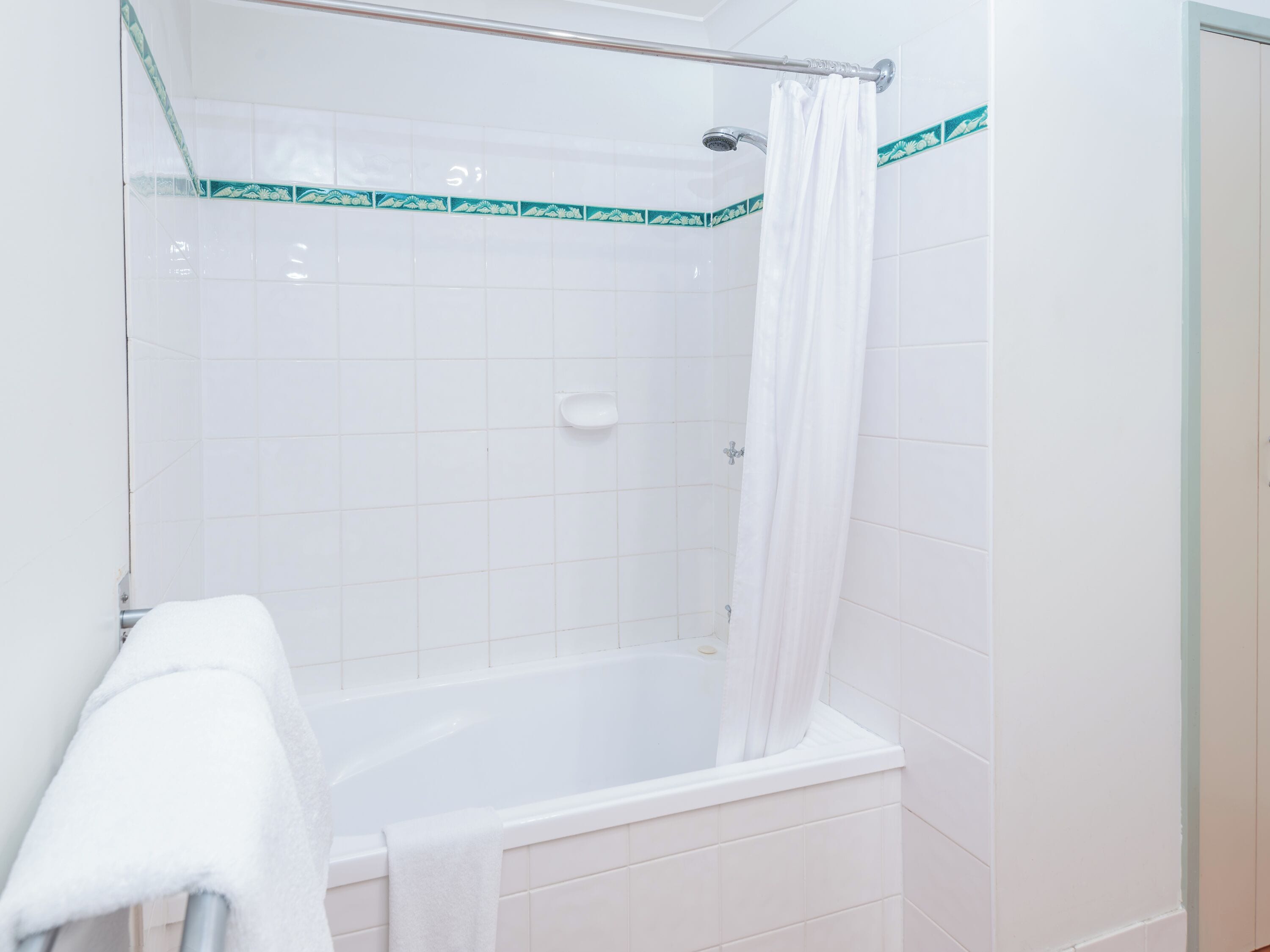 Une salle de bain avec une baignoire, un rideau de douche et une serviette blanche accrochée au mur.