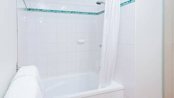 Une salle de bain avec une baignoire, un rideau de douche et une serviette blanche accrochée au mur.