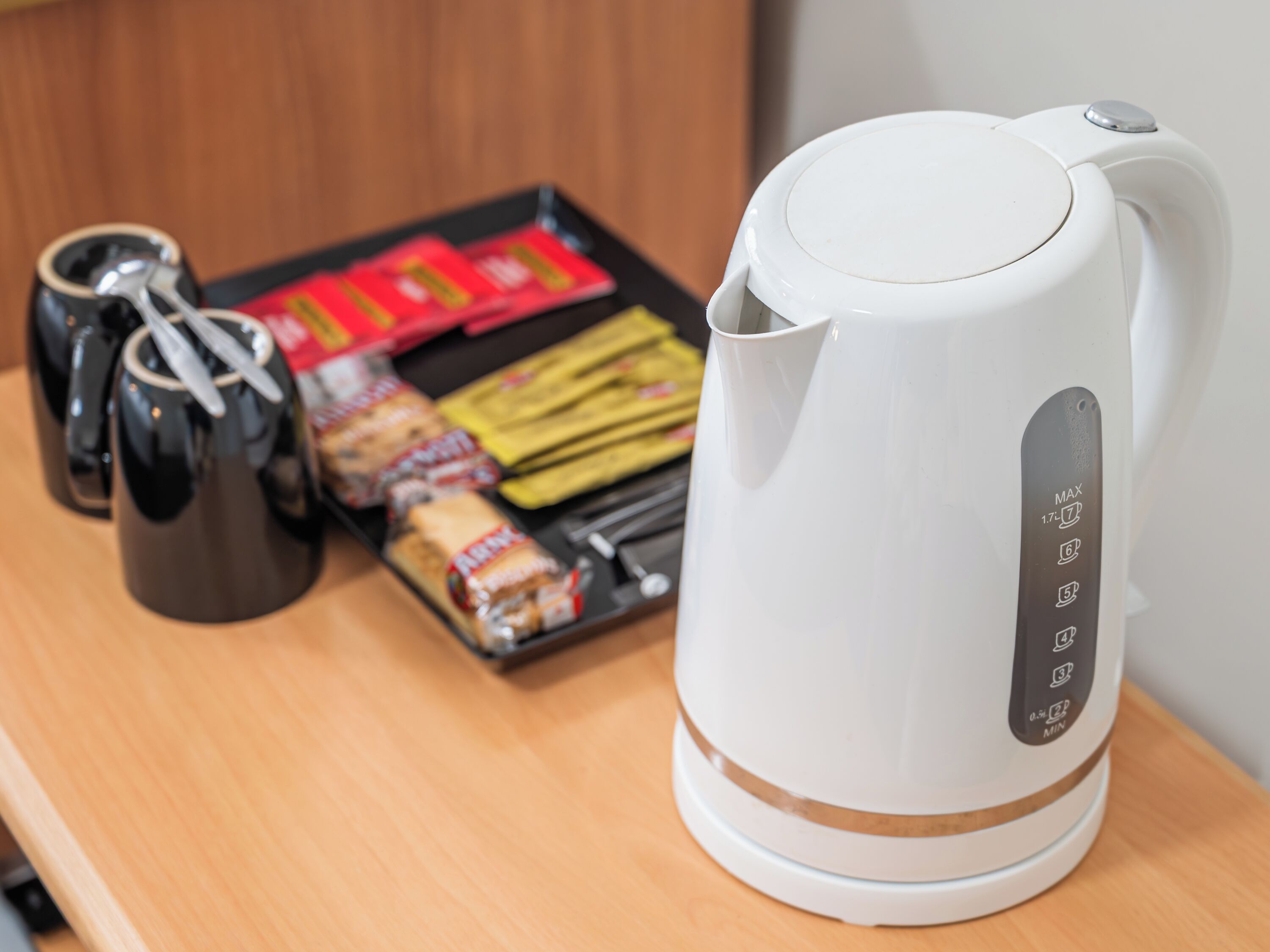 A white electric kettle with a control panel on a wooden surface.