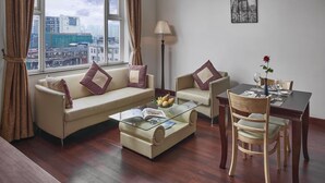 A modern living room with a sofa, armchair, coffee table, and dining table. - Phnom Penh Katari Hotel (Phnom Penh)