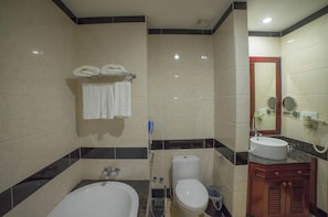 A bathroom with a bathtub, toilet, sink, and a mirror.