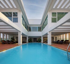 A modern indoor swimming pool with a central staircase and lounge areas on either side. - Phnom Penh Katari Hotel (Phnom Penh)