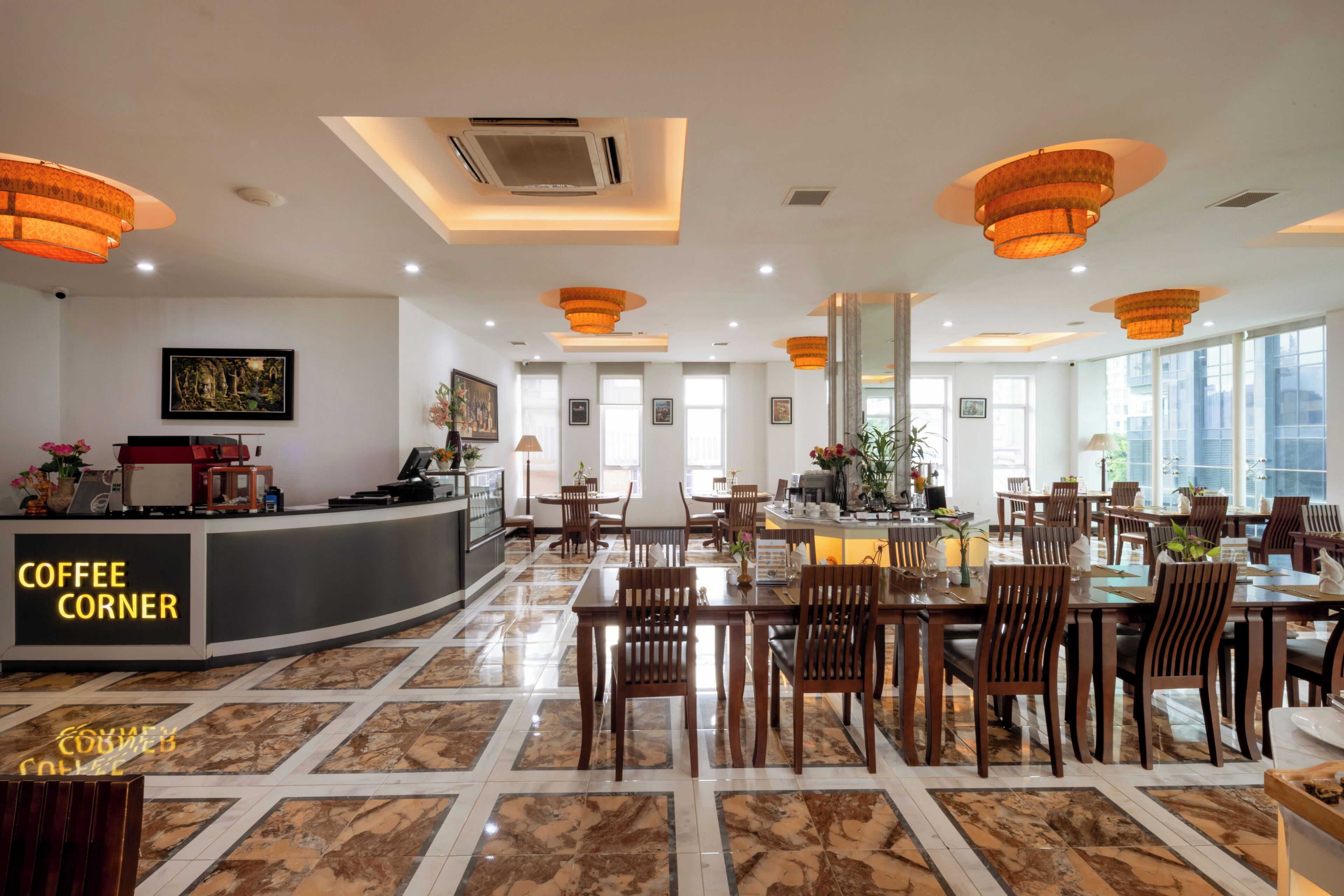 A hotel lobby with a coffee corner, dining area, and large windows.