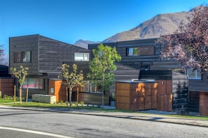 A modern two-story building with a flat roof, large windows, and a mix of wood and metal materials.